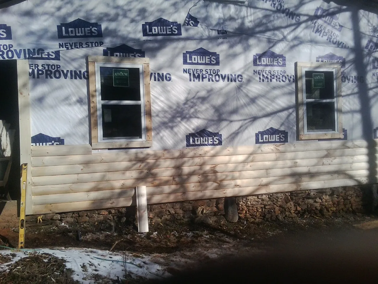 House wrap and new log siding going up on an exterior wall in Caney