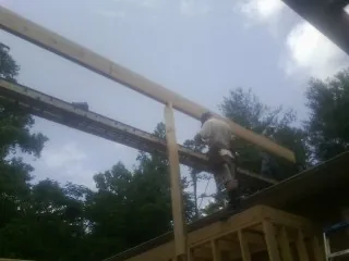 Carpenter setting a ridge beam over a new addition frame — Ice Dam Removal by Roofing Brothers in Caney
