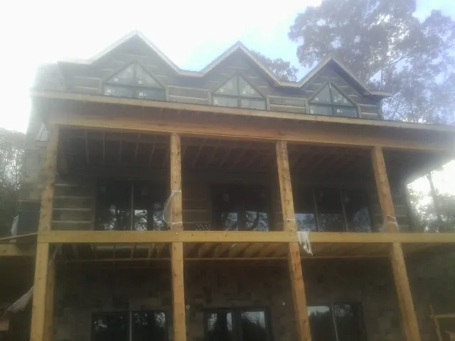 Dormers and porch framing on a large log home under construction — Roof Coating work by our crew in Caney