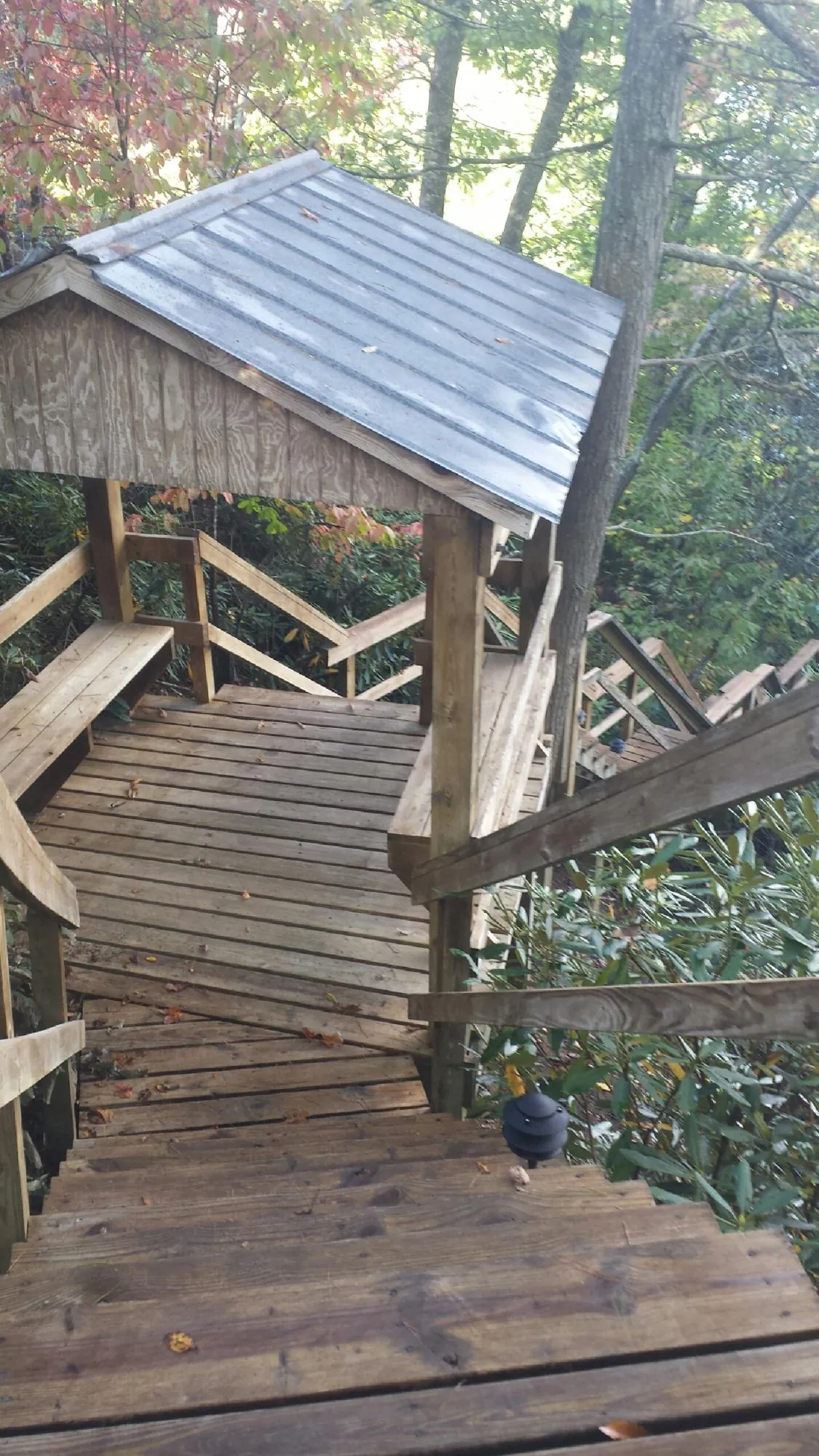 Metal roofed shelter over wooden steps on a wooded walkway — Skylight Repair & Installation work by our crew in Caney