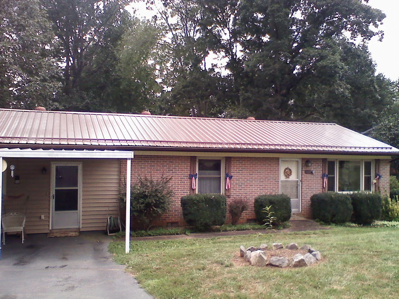 Bronze metal roof and carport on a brick ranch home — Roof Repair work by our crew in Caney