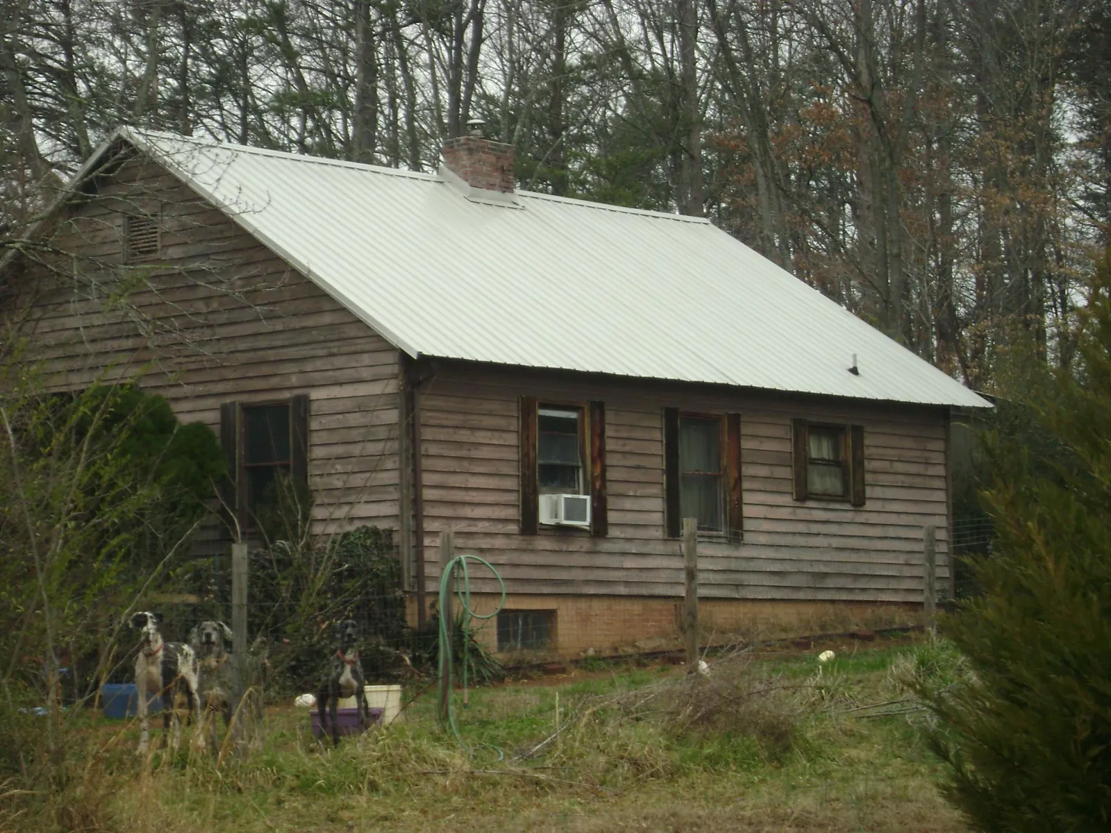 White metal roof on an old wood sided farmhouse, from a Metal Roof Installation job in Caney